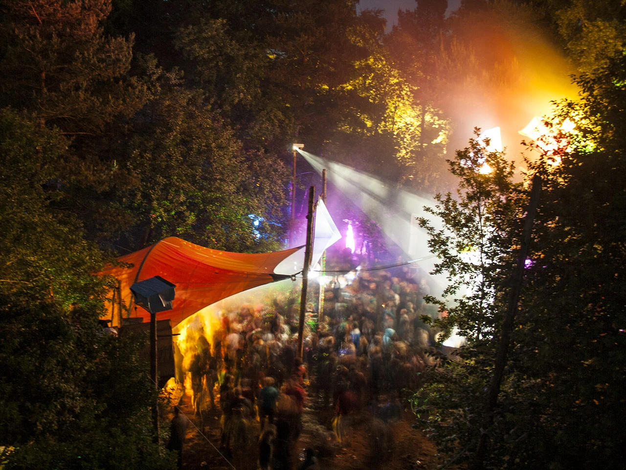 Nächtliches Festival zwischen Bäumen mit beleuchteter Tanzfläche